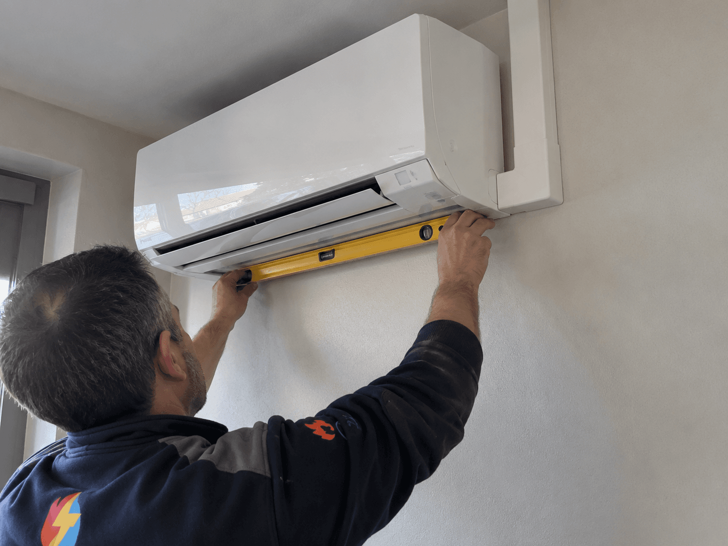 Technicien posant une unité intérieure de climatisation